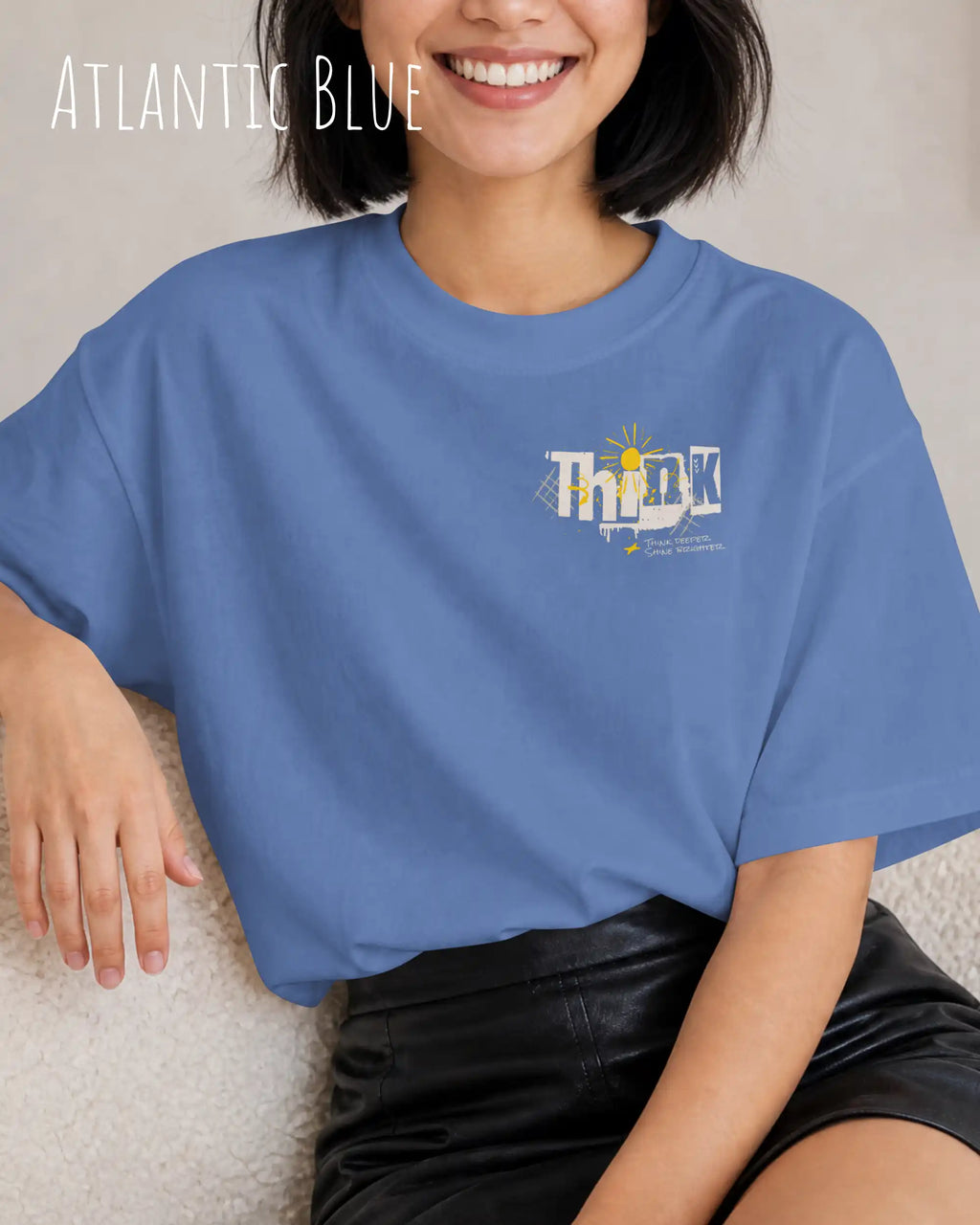 schwarzhaarige frau trägt ein heavyweight oversized design-t-shirt in der farbe atlantic blue mit dem motiv think oben links