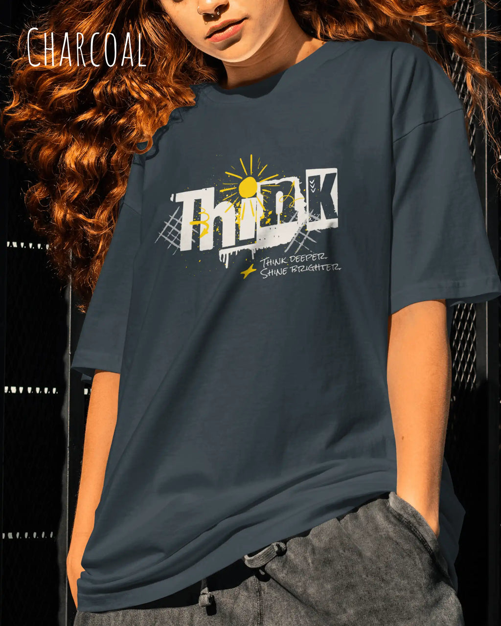 junge frau trägt ein heavyweight oversized design-t-shirt in der farbe charcoal mit dem motiv think.