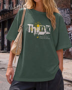 blonde frau trägt ein heavyweight oversized design-t-shirt in der farbe moss green mit dem motiv think.