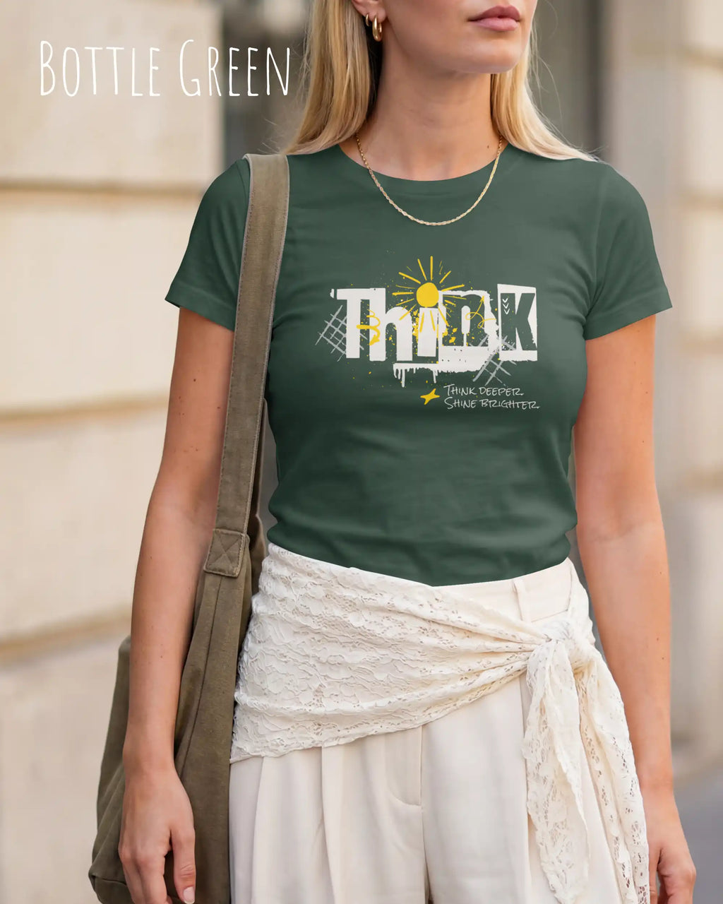 eine blonde frau trägt ein design-t-shirt mit figurbetontem schnitt in der farbe bottle green mit dem Motiv "think deeper shine brighter"