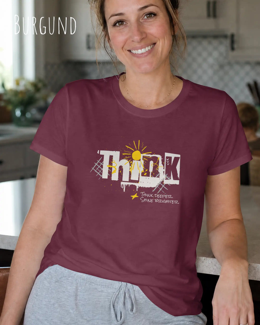 eine frau trägt ein design-t-shirt mit figurbetontem schnitt in der farbe Burgund mit dem Motiv "think deeper shine brighter"