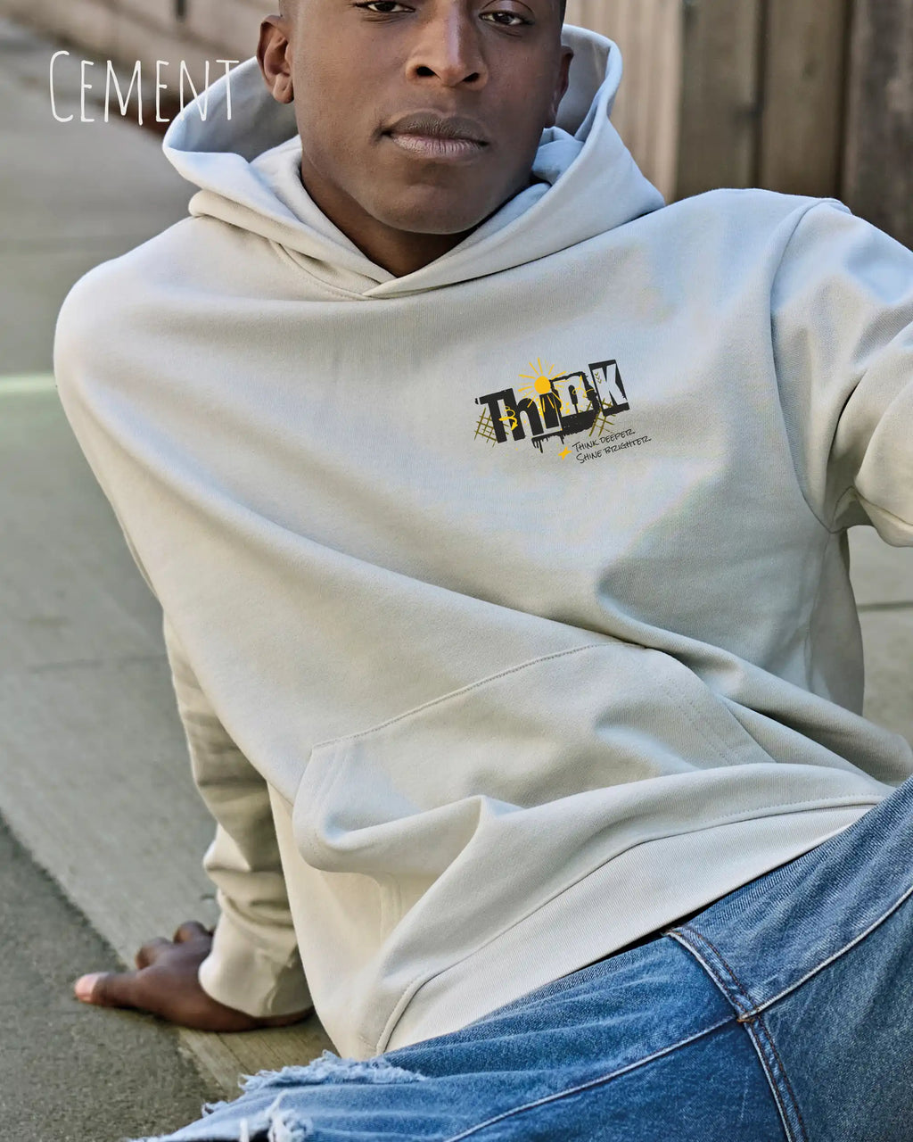Mann trägt das Tee Jays Heavy Loose Fit Hooded Sweatshirt 5162 in der Farbe Cement Mut dem Statement Design THINK.