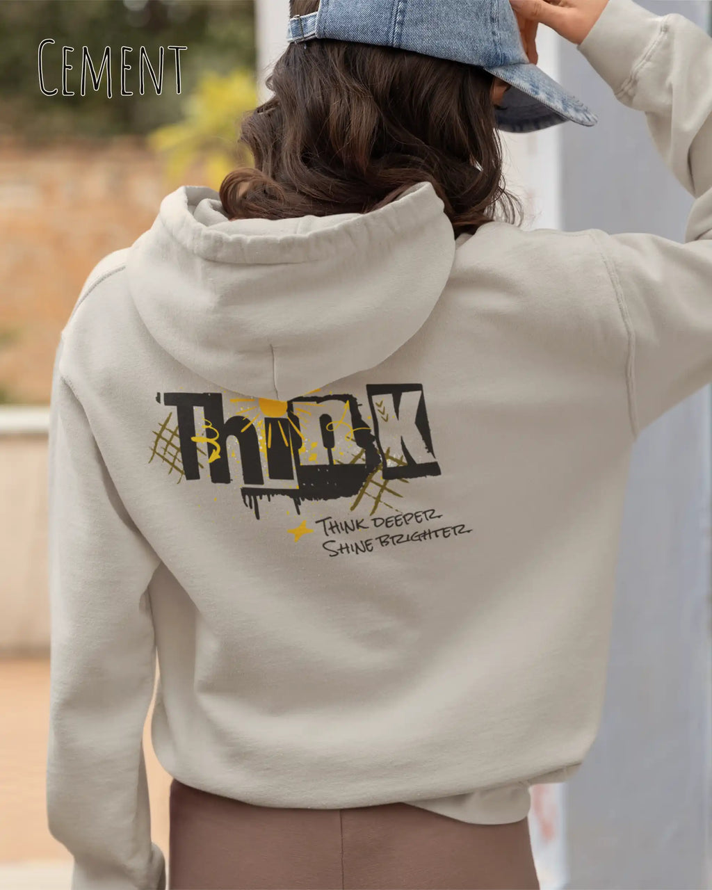 Frau  trägt das Tee Jays Heavy Loose Fit Hooded Sweatshirt 5162 in der Farbe Cement mit dem Statement Design THINK als Backprint.