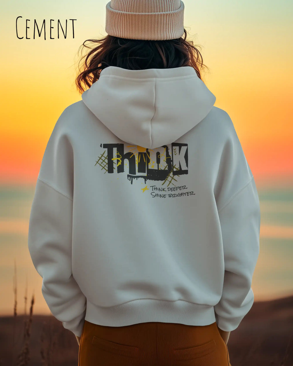 Junge Frau  trägt das Tee Jays Heavy Loose Fit Hooded Sweatshirt 5162 in der Farbe Cement mit dem Statement Design THINK als Backprint.