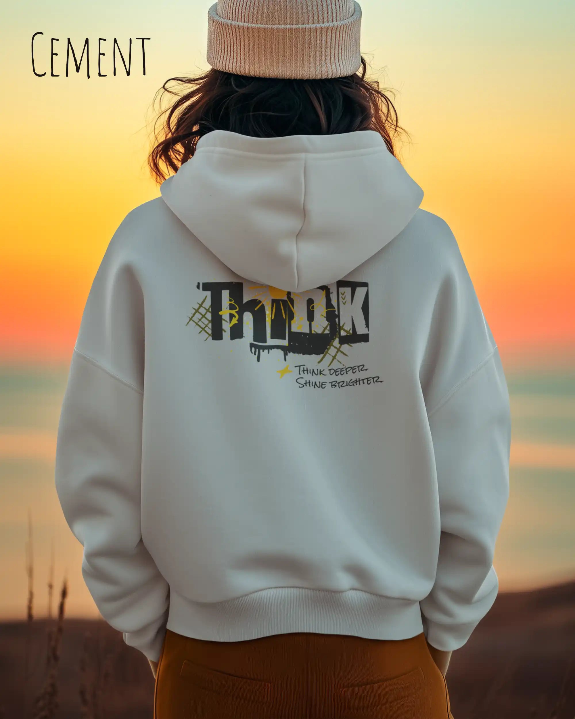 Junge Frau  trägt das Tee Jays Heavy Loose Fit Hooded Sweatshirt 5162 in der Farbe Cement mit dem Statement Design THINK als Backprint.