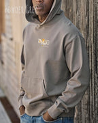 Mann trägt das Tee Jays Heavy Loose Fit Hooded Sweatshirt 5162 in der Farbe powere grey mit dem Statement Design THINK links oben auf der Brust.