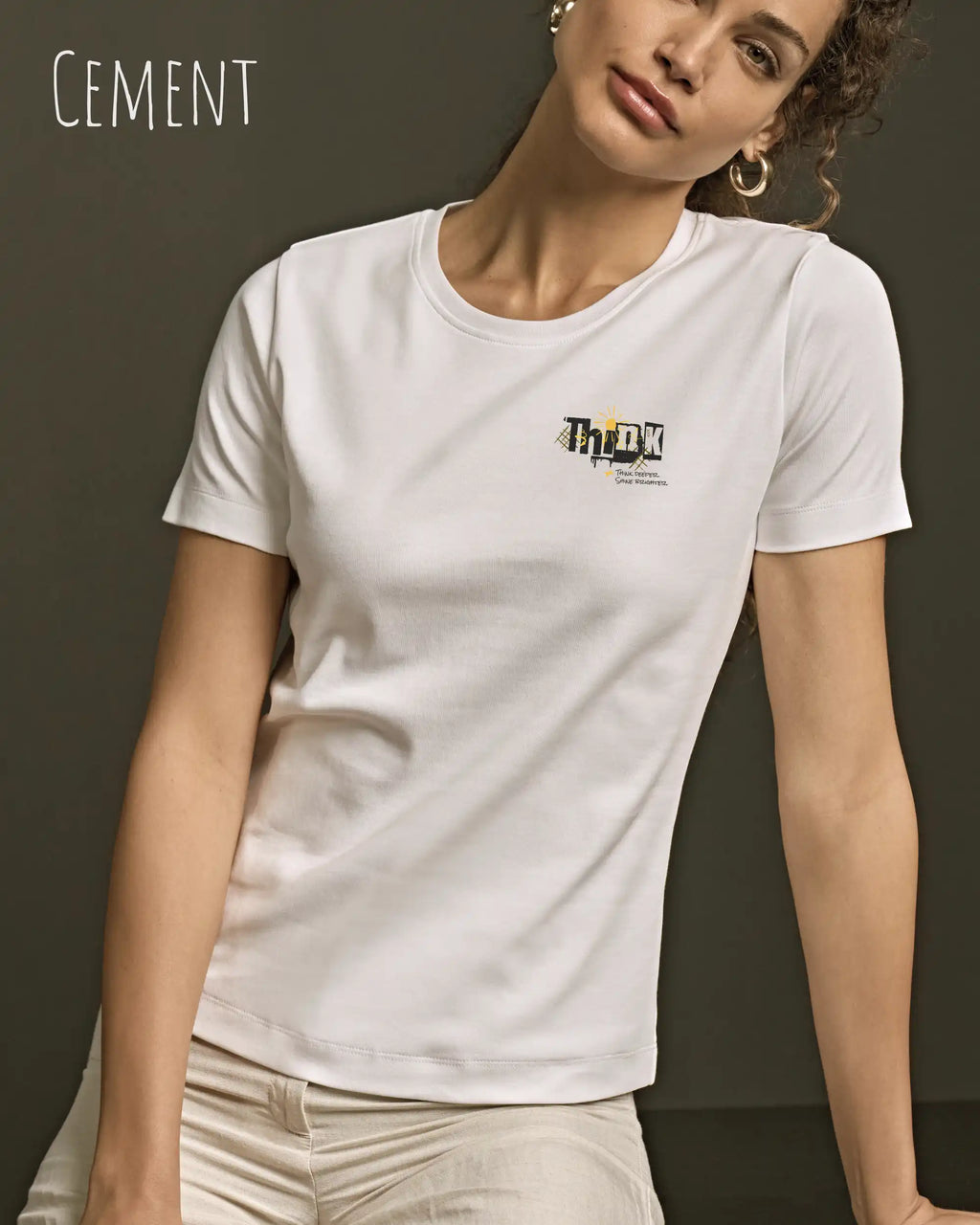 Das Bild zeigt eine frau, die ein feminines Grafik t-shirt in cement und mit dem Statement-design think deeper trägt.
