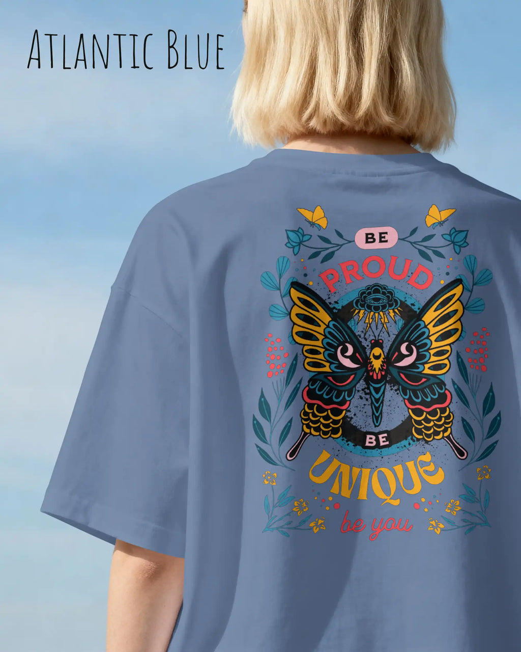 Frau trägt das Heavyweight Oversized T-Shirt AWDis 240 T in der Farbe atlantic blue mit dem Design BE PROUD BE YOU auf dem Rücken.