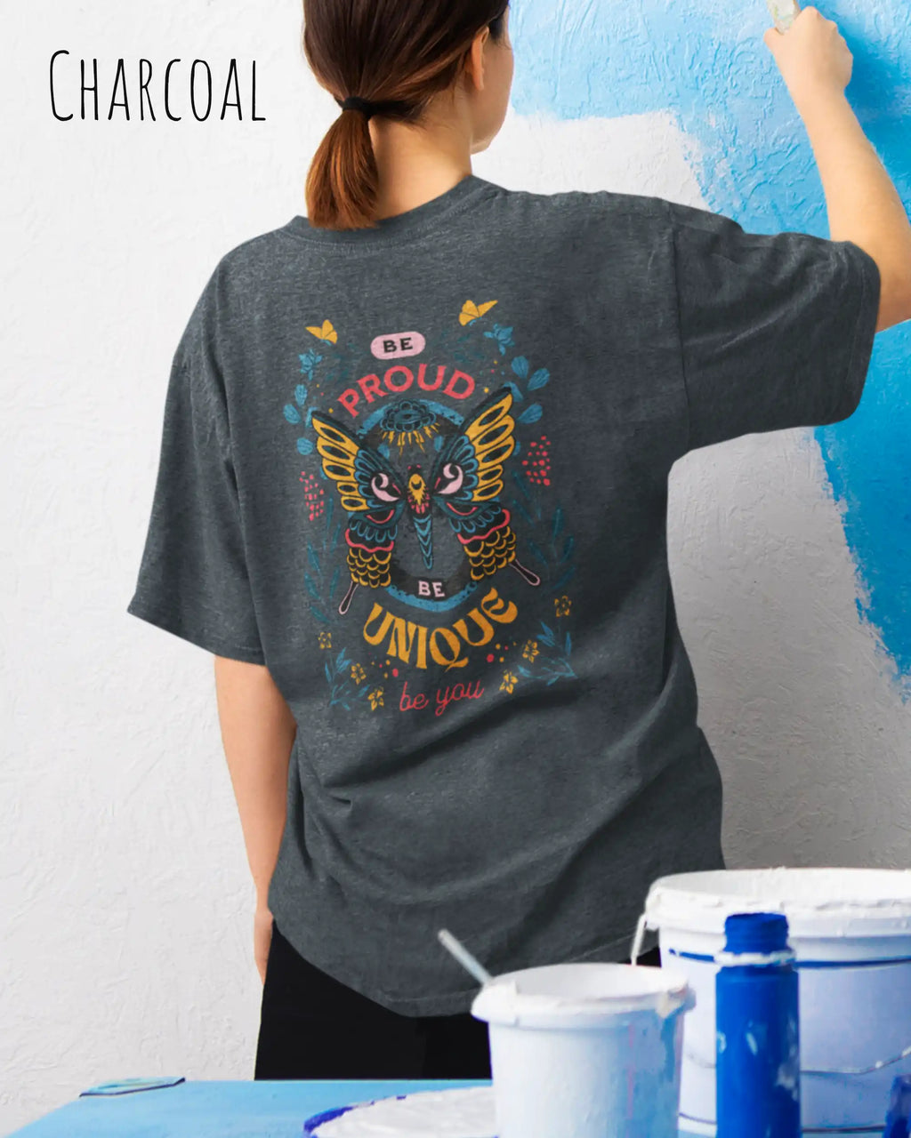 Frau trägt das Heavyweight Oversized T-Shirt AWDis 240 T in der Farbe charcoal  mit dem Design BE PROUD BE YOU auf dem Rücken.