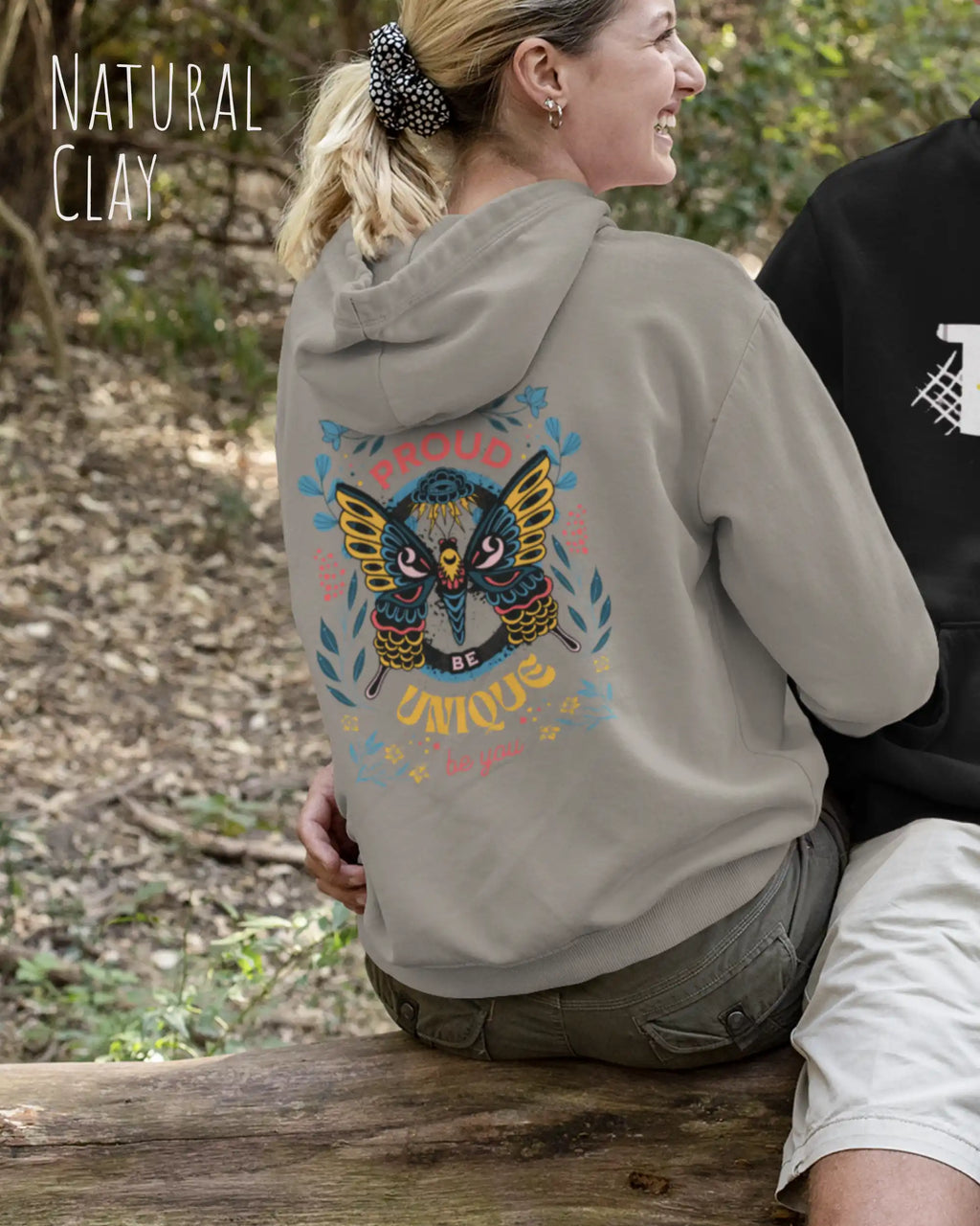 frau trägt streetwear hoodie im oversize fit in farbe natural clay mit be proud motiv hinten