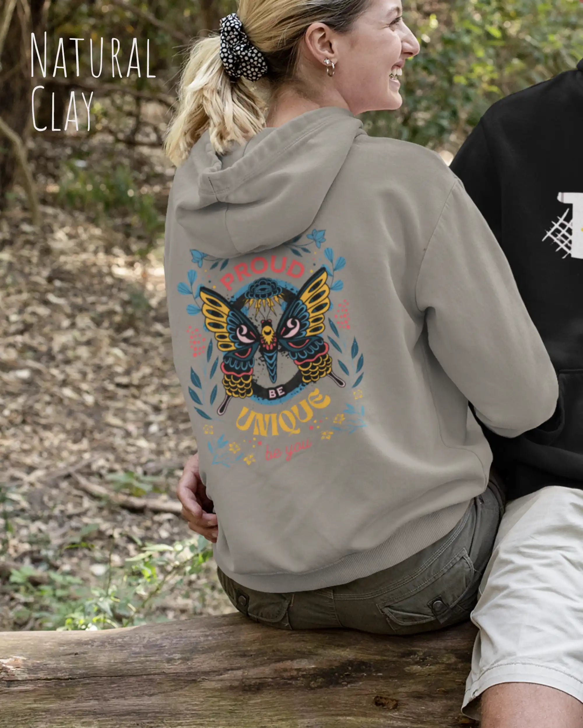 frau trägt streetwear hoodie im oversize fit in farbe natural clay mit be proud motiv hinten
