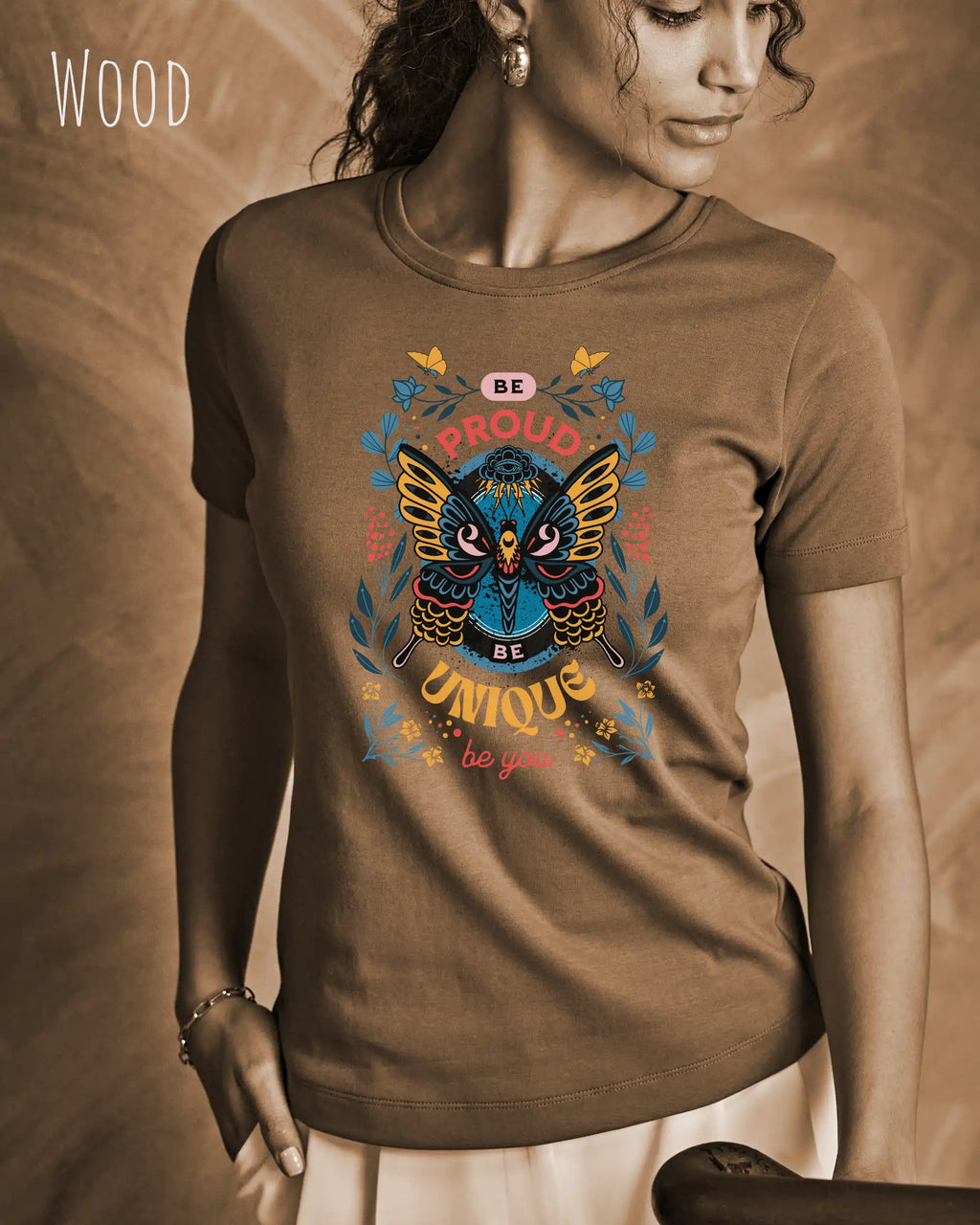 Das Bild zeigt eine frau, die ein design-t-shirt in der farbe wood mit der boho-Grafik be proud trägt.