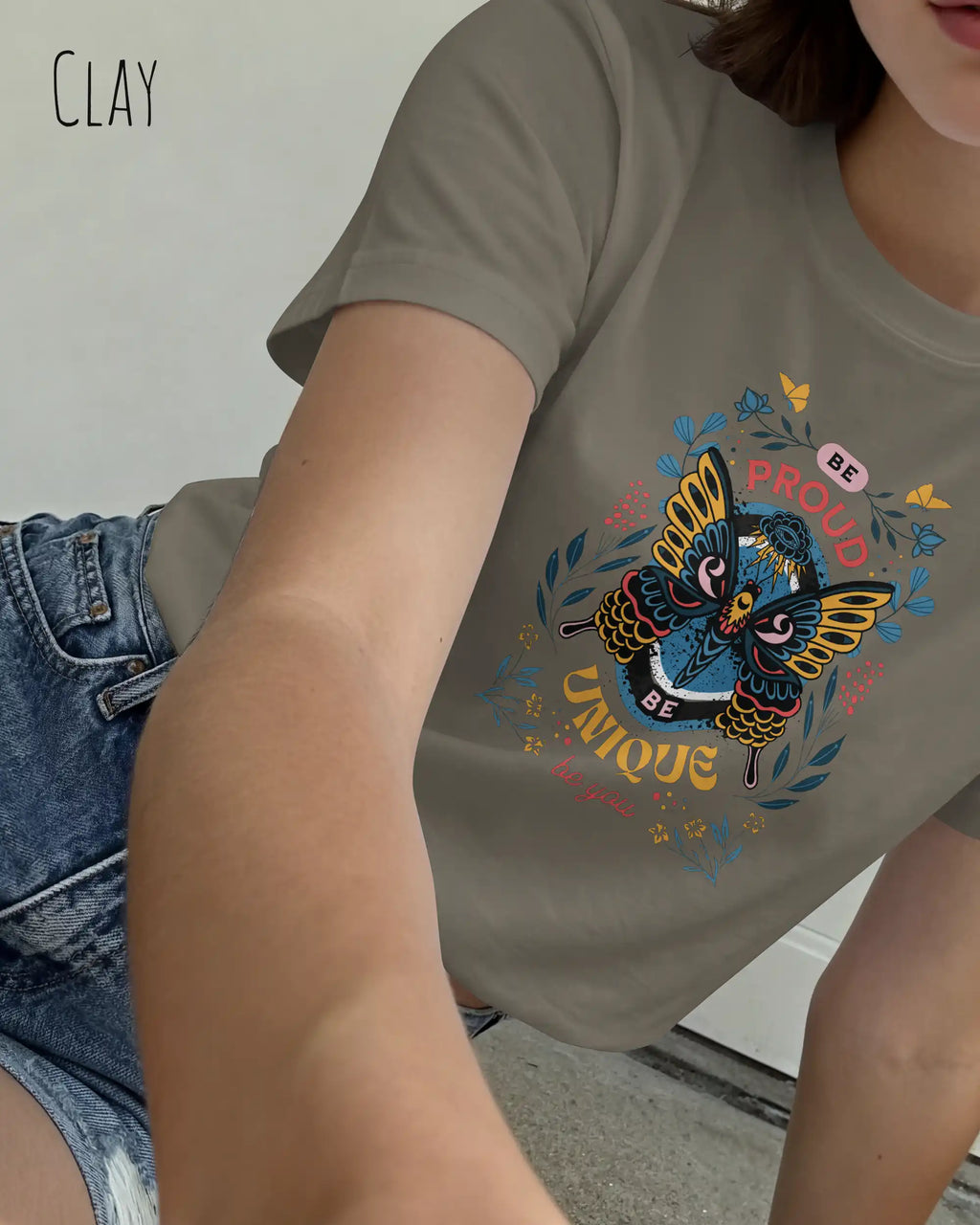 Das Bild zeigt eine junge frau, die ein design-t-shirt in der farbe clay mit der boho-Grafik be proud trägt.