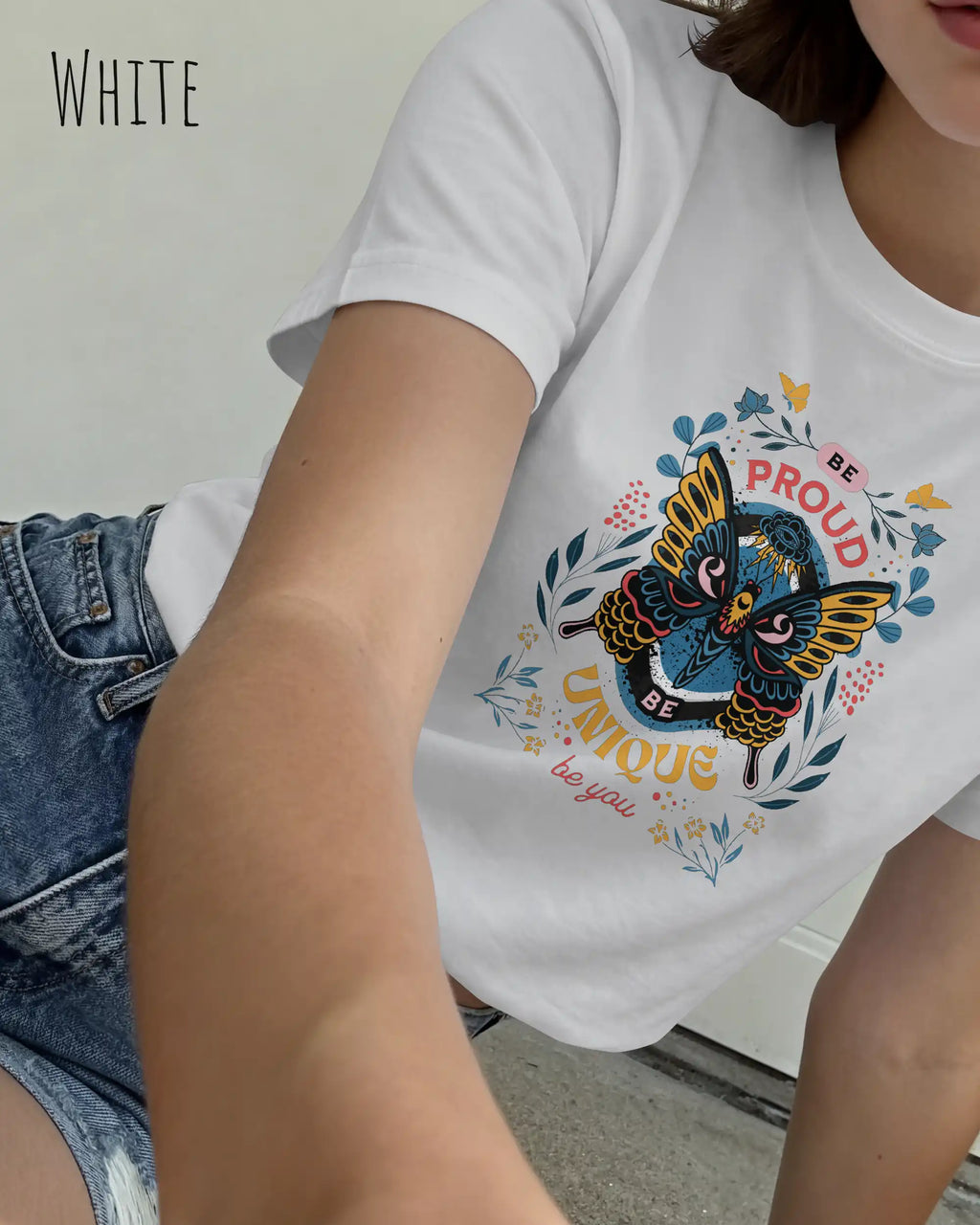 Das Bild zeigt eine liegende frau, die ein design-t-shirt in der farbe white mit der boho-Grafik be proud trägt.