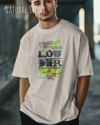 Junger Mann  trägt das Heavyweight Oversized T-Shirt AWDis 240 T in der Farbe natural stone  mit dem Design LOUDER vorne auf der Brust.