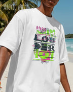 Mann am Strand  trägt das Heavyweight Oversized T-Shirt AWDis 240 T in der Farbe arctic white mit dem Design LOUDER auf der Brust.