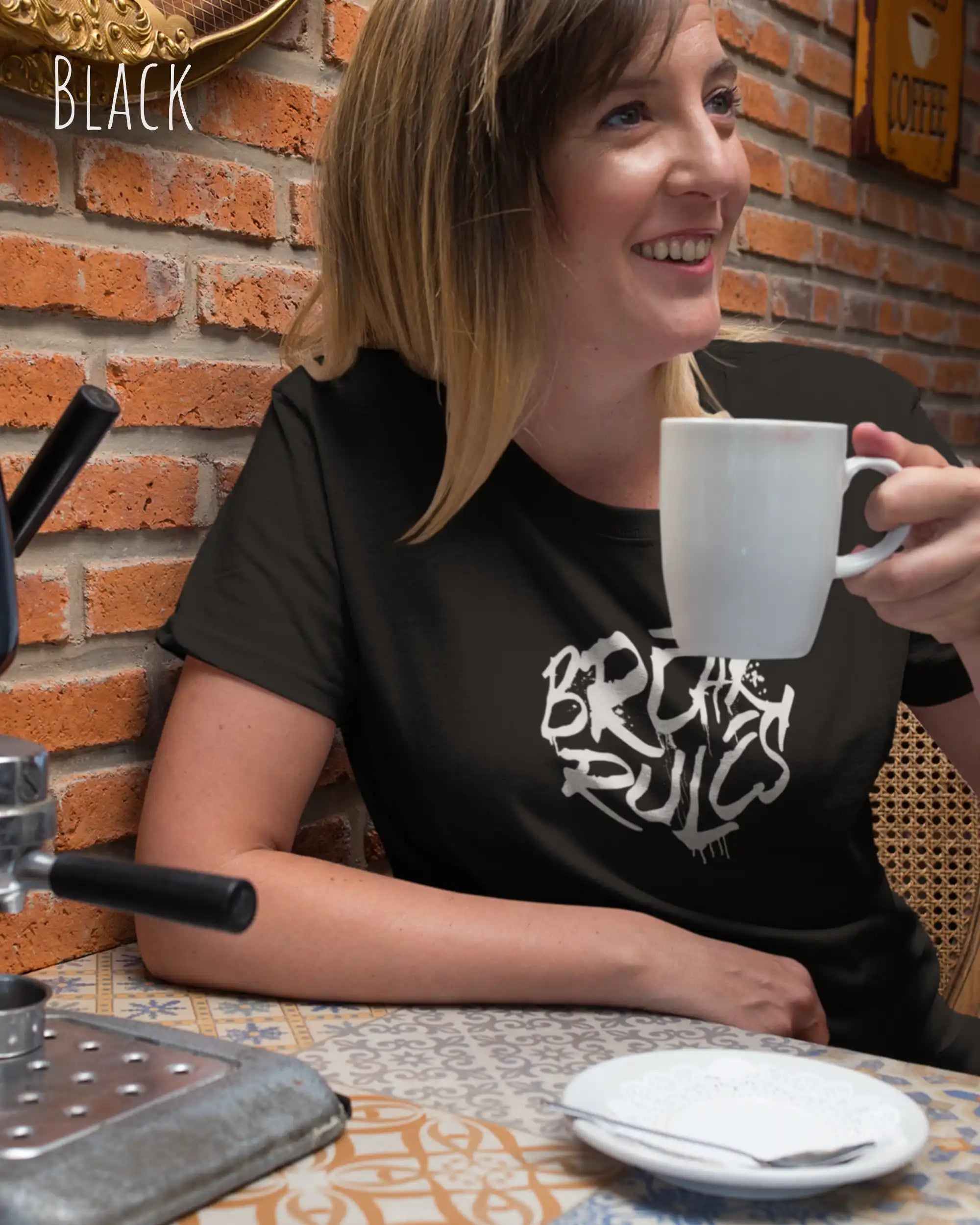 Frau im Cafe  trägt das Bio-Baumwolle T-Shirt Tee Jays Urban Luxury Tee 1150 in der Farbe black mit dem Design BREAK RULES auf der Brust.