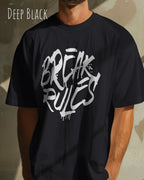 mann trägt ein oversized heavyweight design-t-shirt in der farbe deep black mit dem frontprint motiv break rules.