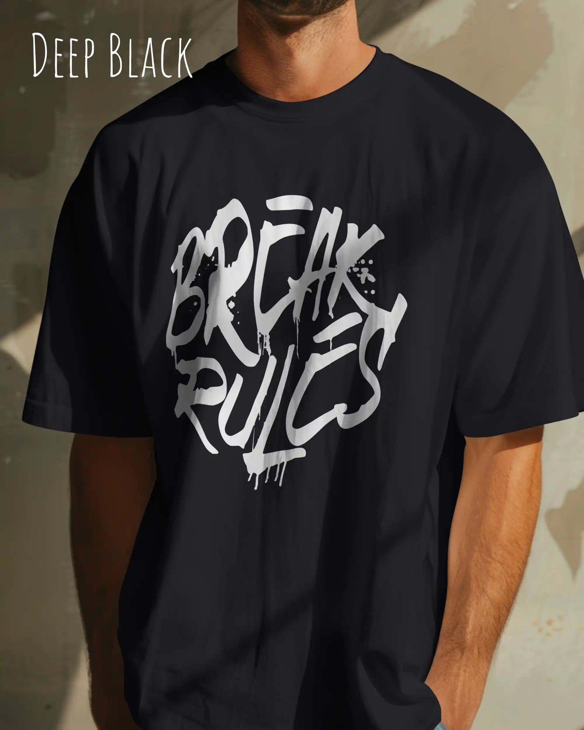 mann trägt ein oversized heavyweight design-t-shirt in der farbe deep black mit dem frontprint motiv break rules.