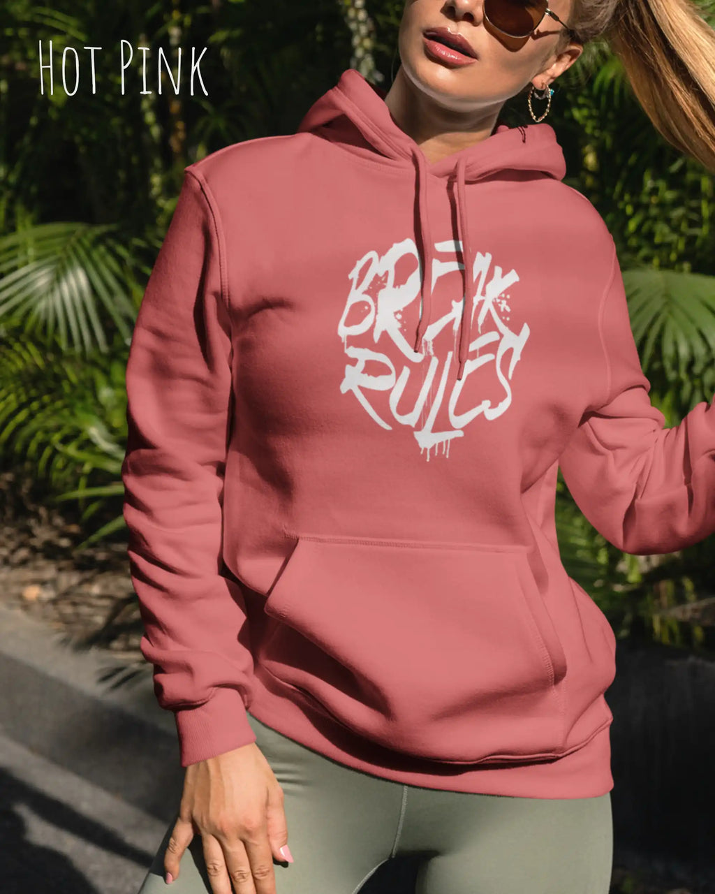 Frau trägt hoodie im feminine fit aus weicher baumwollmischung in farbe hot pink mit break rules motiv auf der Brust