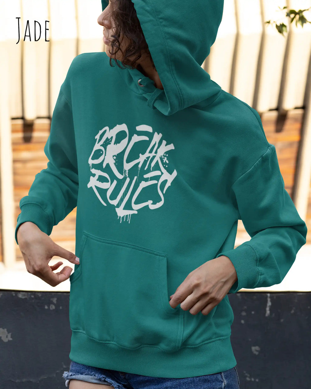 Frau trägt hoodie im feminine fit aus weicher baumwollmischung in farbe jade mit break rules motiv auf der Brust