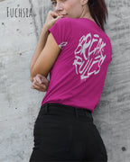 Frau trägt ein feminines Design-T-Sjhirt in der farbe fuchsia mit dem Statement break rules mittig auf dem rücken