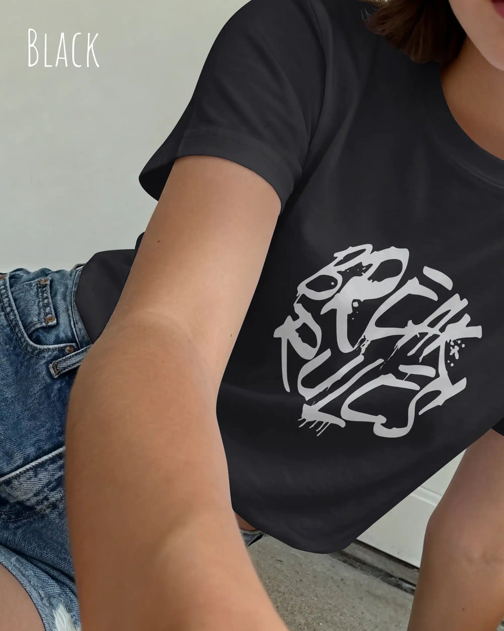 Eine  frau trägt ein design t-shirt mit femininem schnitt in der farbe black und mit der grafik "break rules" vorne auf der brust