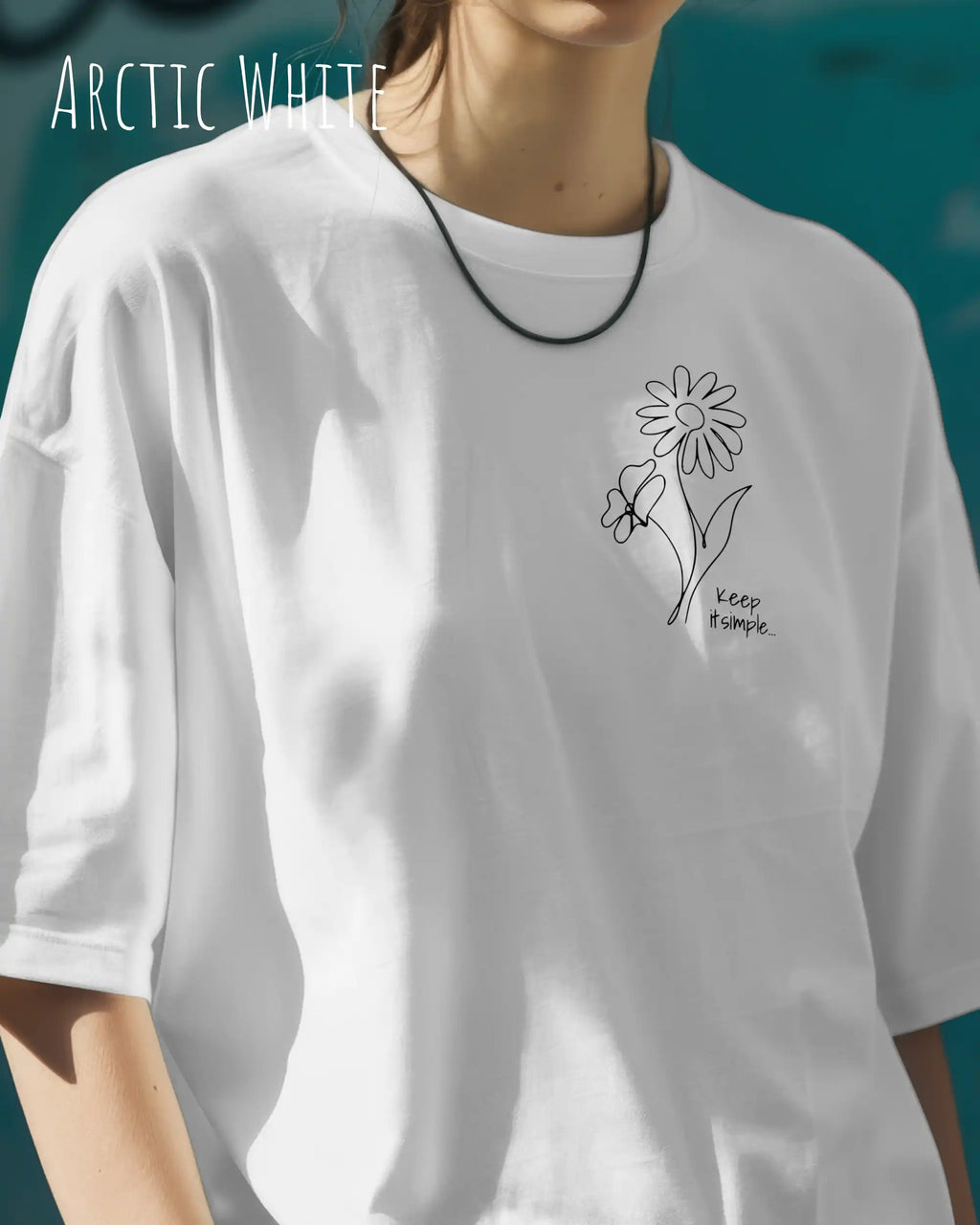 frau trögt ein oversized heavyweight design-t-shirt in der farbe arctic white und mit dem motiv keep it simple links oben