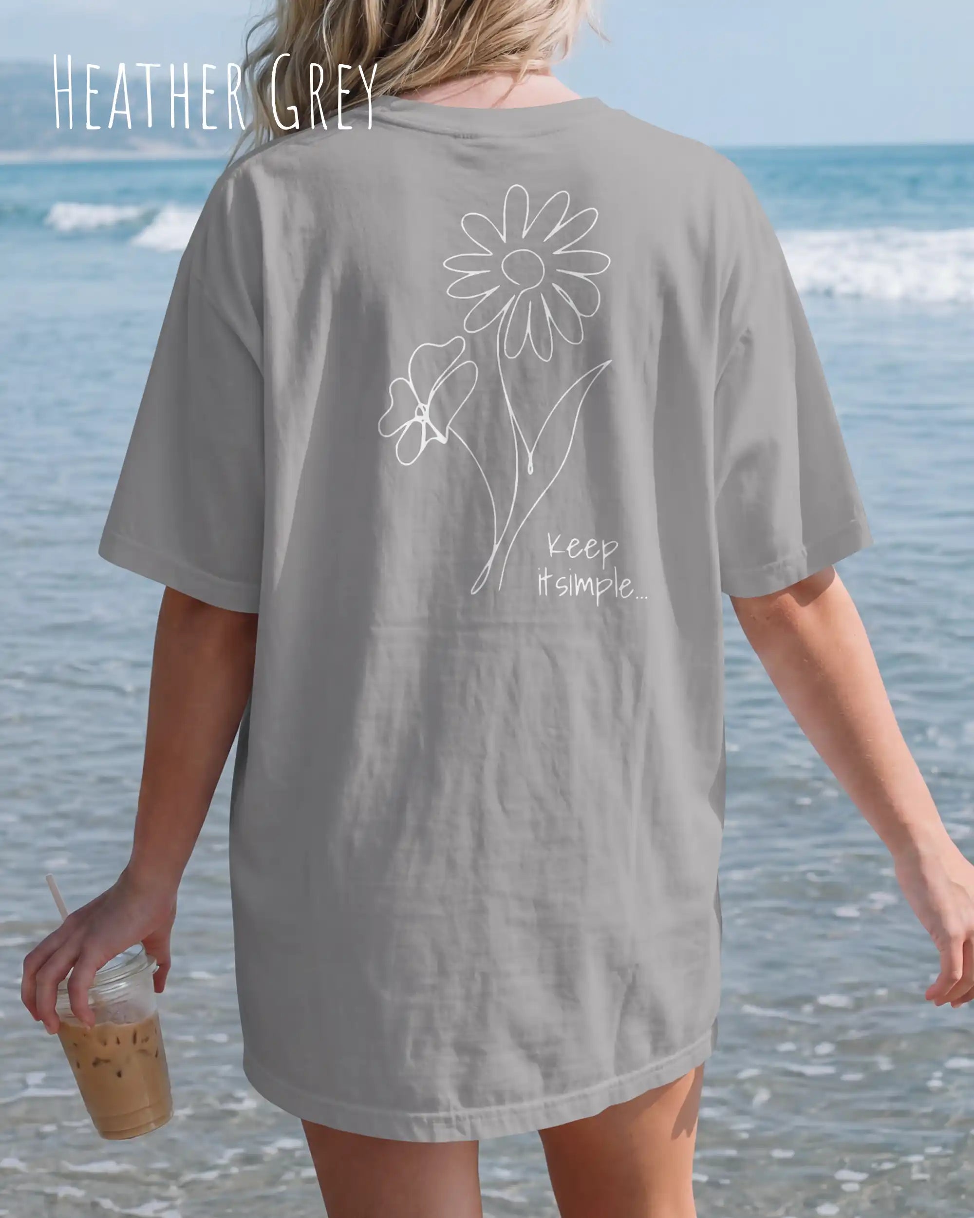 blonde frau trögt ein oversized heavyweight design-t-shirt in der farbe heather grey und mit dem backprint keep it simple.