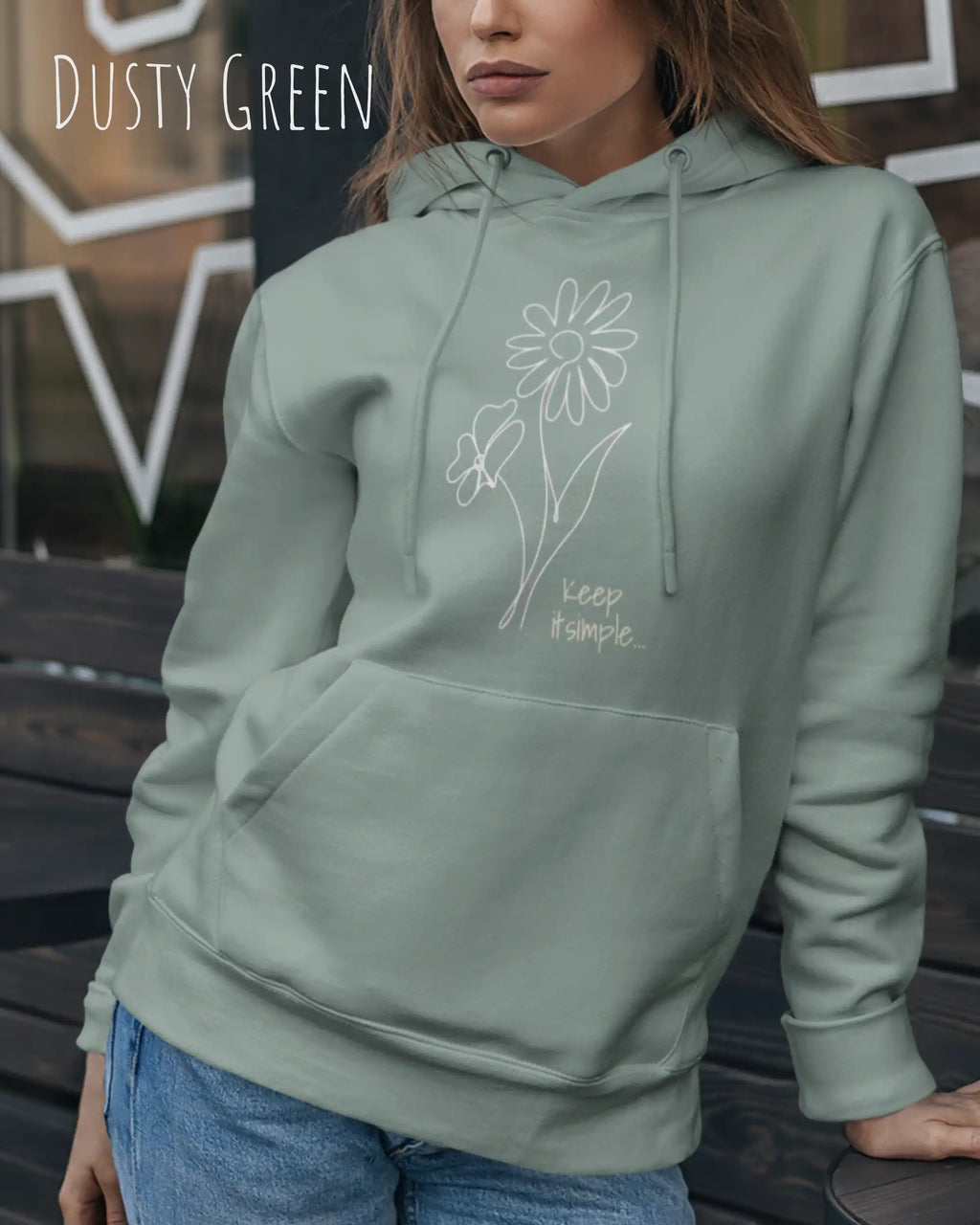 Frau trägt hoodie im feminine fit aus weicher baumwollmischung in farbe dusty green mit keep it simple motiv auf der Brust