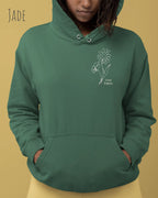 Frau trägt hoodie im feminine fit aus weicher baumwollmischung in farbe jade mit keep it simple motiv oben links