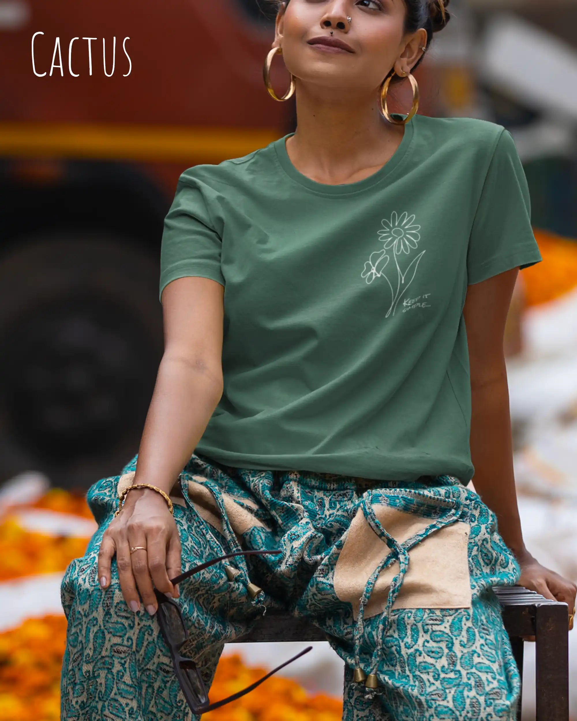 Das Bild zeigt eine junge frau, die ein design-t-shirt ind der farbe cactus mit dem grafik-motiv keeo it simple trägt.