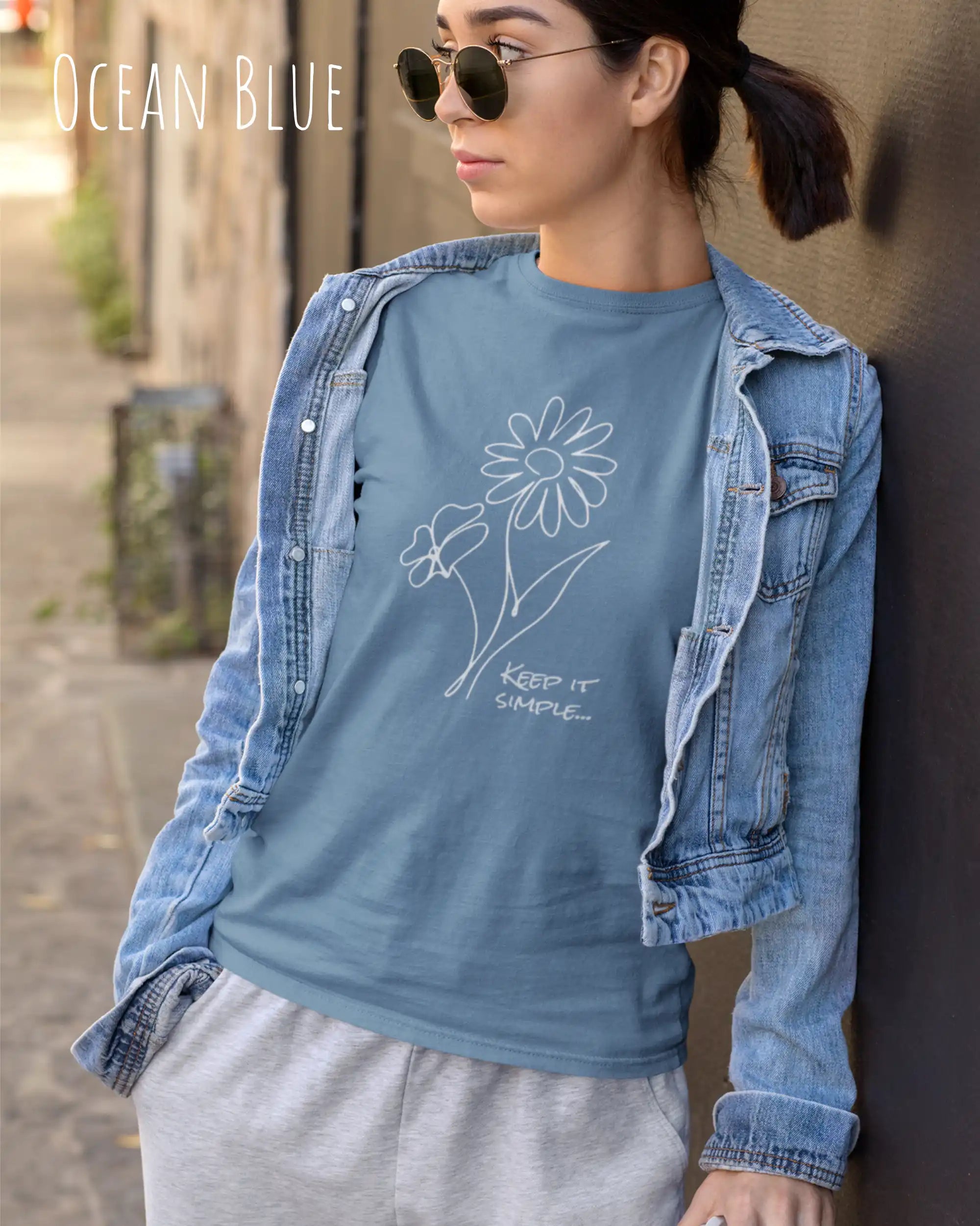 Das Bild zeigt eine junge frau, die ein design-t-shirt ind der farbe oceanblue mit dem grafik-motiv keeo it simple trägt.