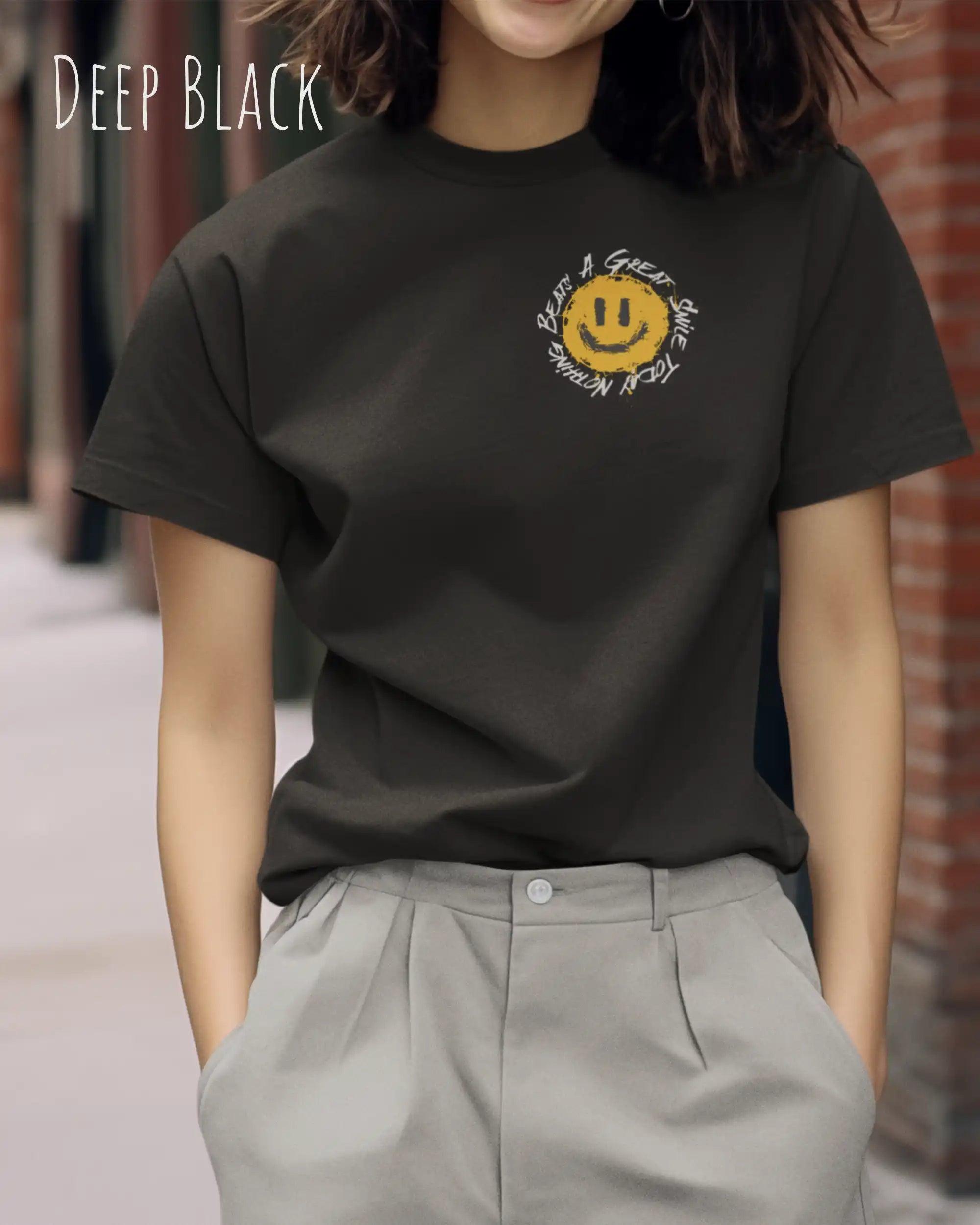 Das Bild zeigt eine frau, die ein Grafik-Design-T-Shirt in der farbe deep black mit dem Design Nothing beats a great smile trägt.