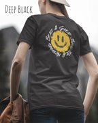 Das Bild zeigt eine frau, die ein Grafik-Design-T-Shirt in der farbe deep black mit dem backprint Design Nothing beats a great smile trägt.