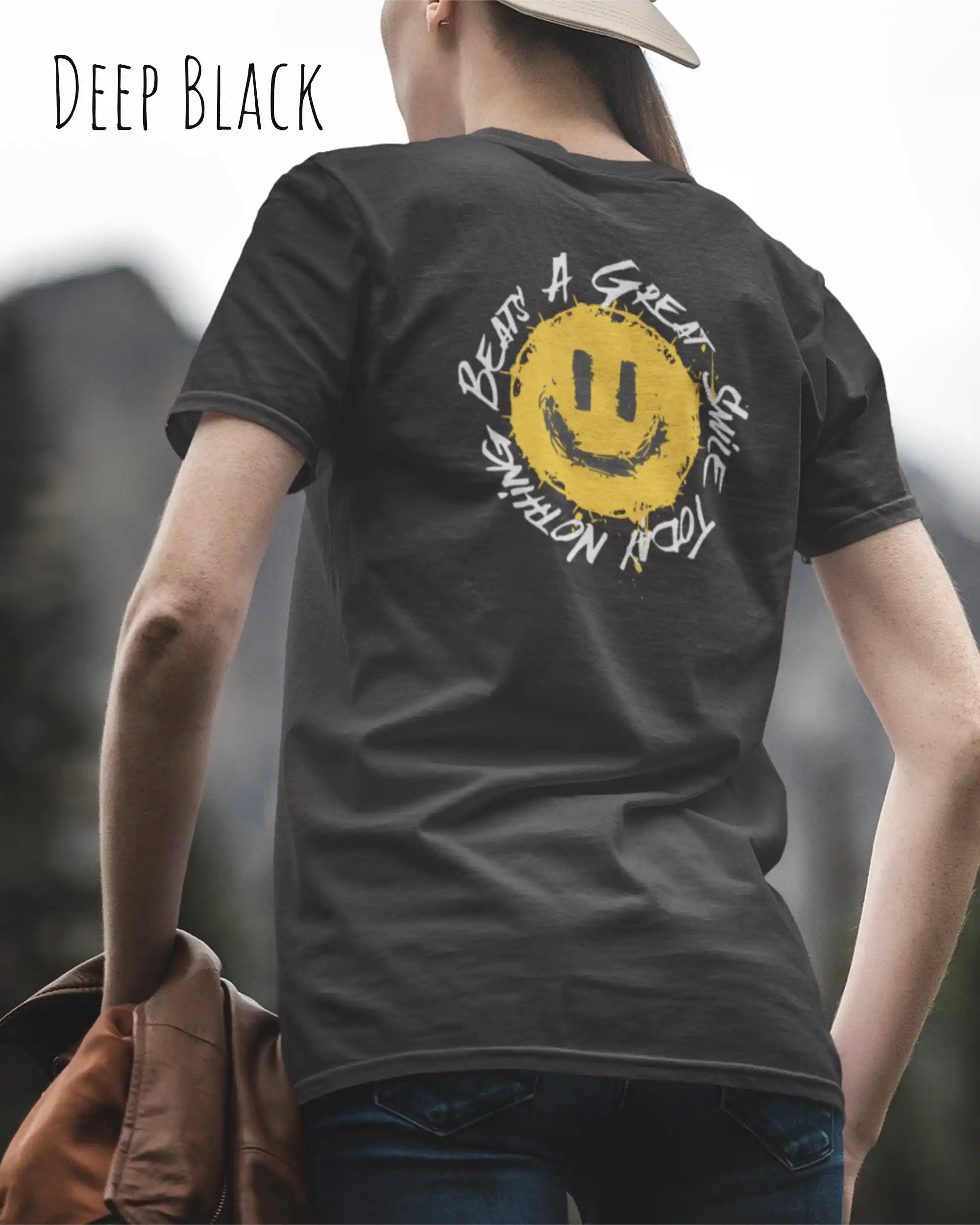 Das Bild zeigt eine frau, die ein Grafik-Design-T-Shirt in der farbe deep black mit dem backprint Design Nothing beats a great smile trägt.