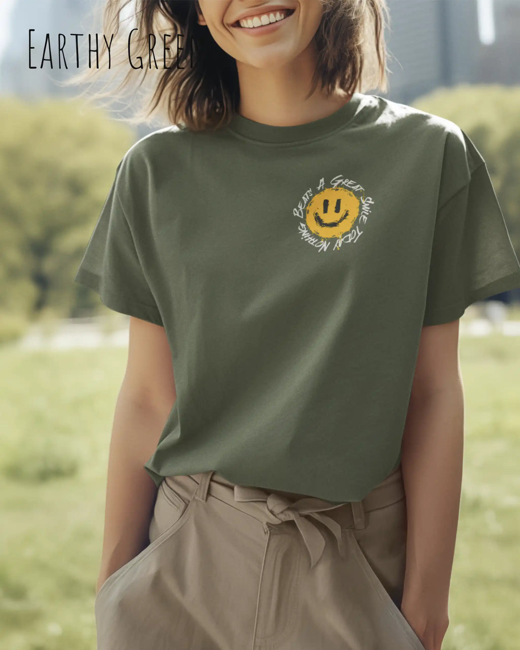 Das Bild zeigt eine frau, die ein Grafik-Design-T-Shirt in der farbe earthy green mit dem Design Nothing beats a great smile trägt.