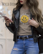 Das Bild zeigt eine frau, die ein Grafik-Design-T-Shirt in der farbe Mocca brown  mit dem Design Nothing beats a great smile trägt.