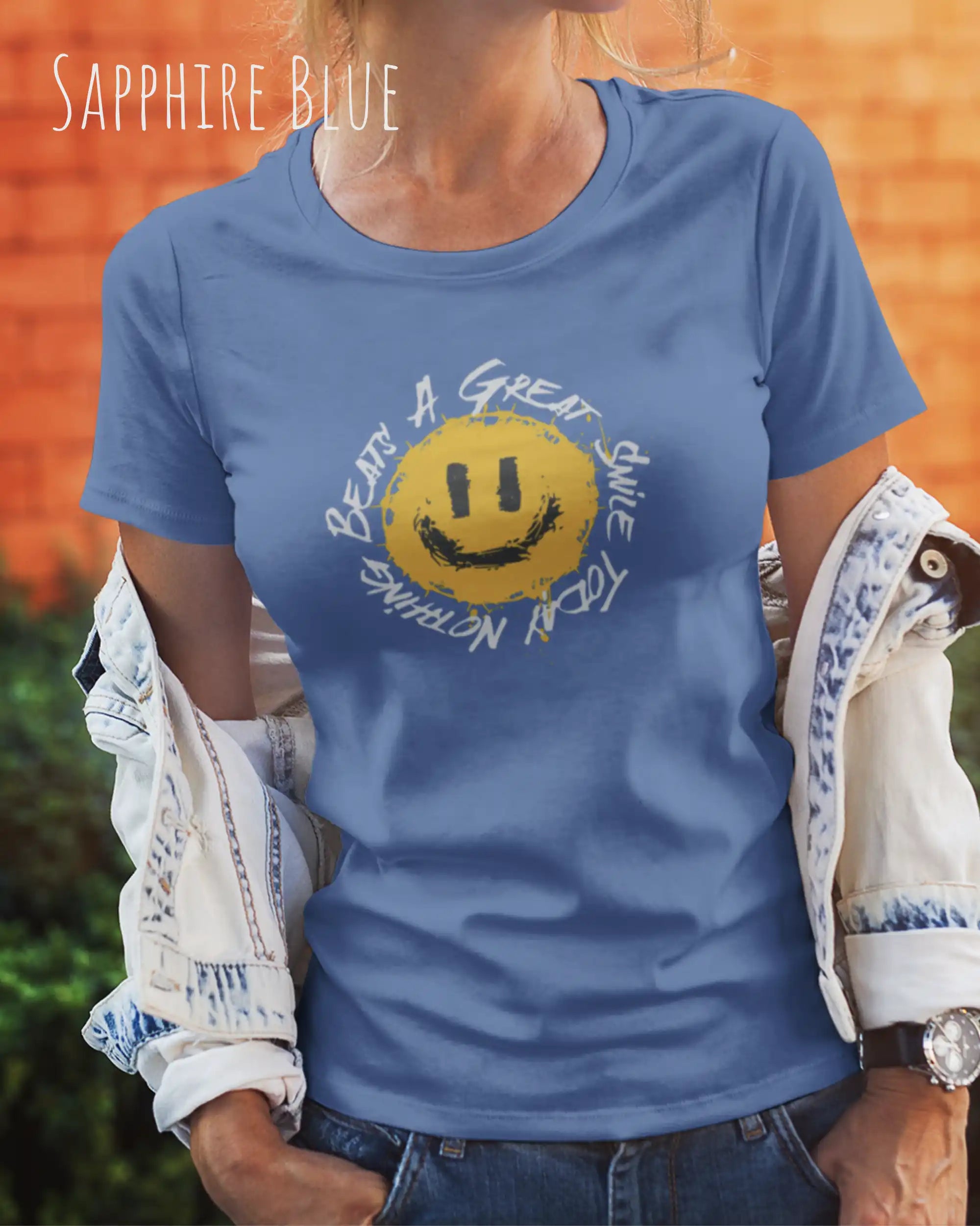 Das Bild zeigt eine frau, die ein Grafik-Design-T-Shirt in der farbe sapphire blue mit dem Design Nothing beats a great smile trägt.