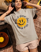 lächelnde frau mit Kopfhörer  trägt ein oversized heavyweight t-shirt  in der farbe natural stone  mit dem design nothing beats a great smile today.