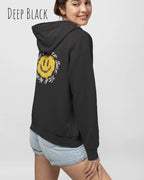 Das Bild zeigt eine frau, die einen einen femininen Hoodie in deep black mit dem backprint Design nothing beats a great smile trägt.