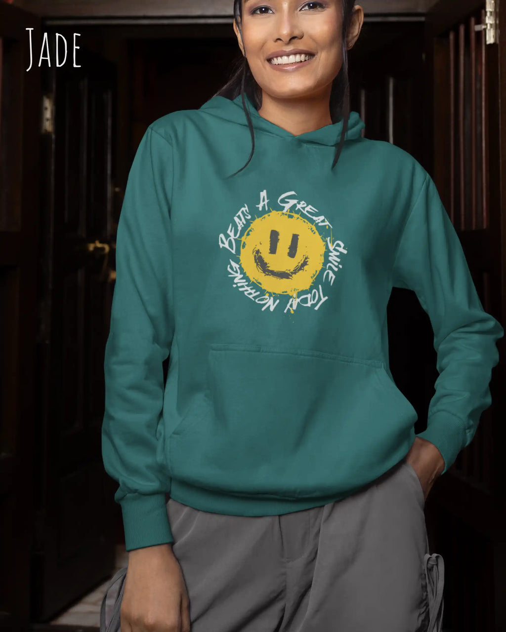 Das Bild zeigt eine frau, die einen einen femininen Hoodie in jade mit dem Design nothing beats a great smile trägt.