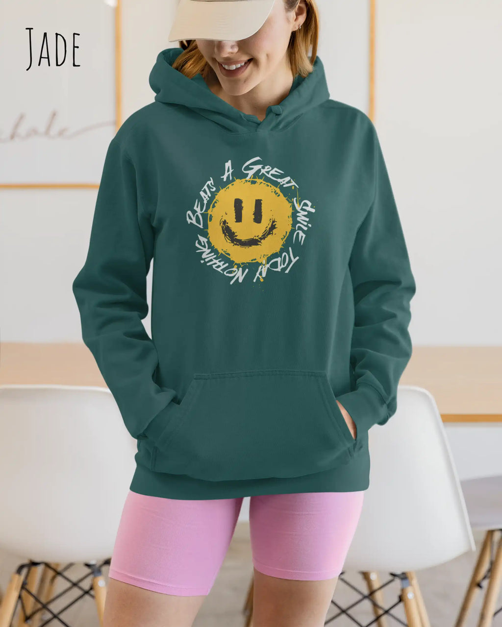 Das Bild zeigt eine Frau, die einen Design-Hoodie in der Farbe jade und mit der Grafik Nothing beats a great smile trägt.