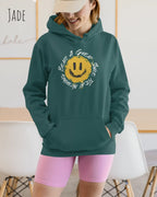 Das Bild zeigt eine Frau, die einen Design-Hoodie in der Farbe jade und mit der Grafik Nothing beats a great smile trägt.