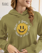 Das Bild zeigt eine lächelnde Frau, die einen Design-Hoodie in der Farbe khaki und mit der Grafik Nothing beats a great smile trägt.