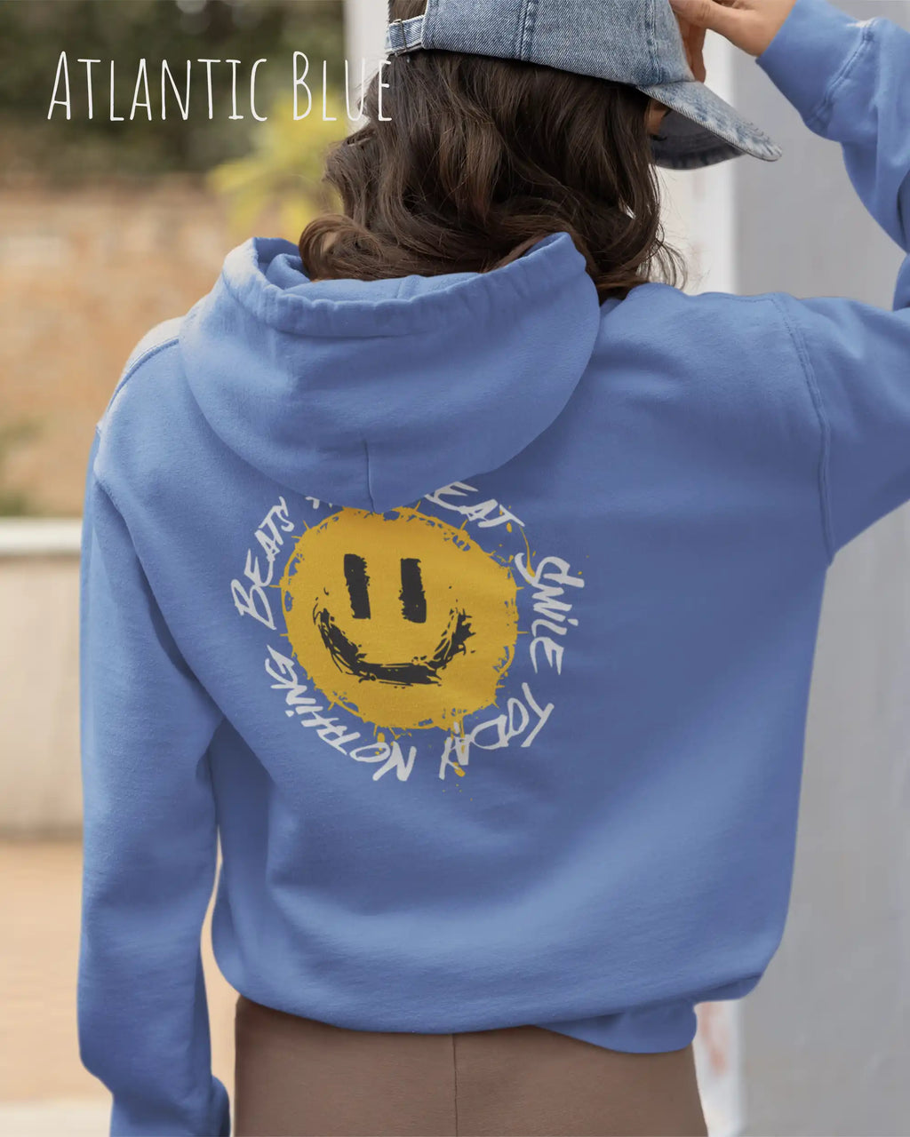 Das Bild zeigt eine frau, die einen  oversized Grafik hoodie in der farbe atlantic blue mit dem design notihing beats a great smile trägt.