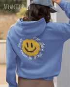 Das Bild zeigt eine frau, die einen  oversized Grafik hoodie in der farbe atlantic blue mit dem design notihing beats a great smile trägt.