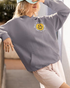 Das Bild zeigt eine frau, die einen  oversized Grafik hoodie in der farbe dusty lilac mit dem design notihing beats a great smile trägt.
