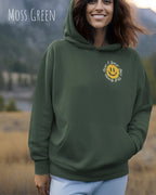 Das Bild zeigt eine frau, die einen  oversized Grafik hoodie in der farbe moss green mit dem design notihing beats a great smile trägt.