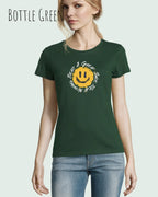 Eine Frau trägt das Basic Design-T‑Shirt im Feminine Fit in der Farbe bottle green.. Das Design zeigt das Statement NOTHING BEATS A SMILE.